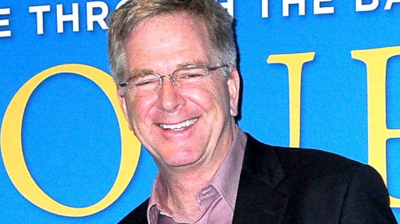 Travel TV host Rick Steves smiles in glasses at an event