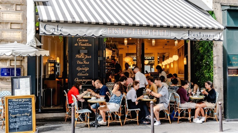 Diners sit at tables outside a French bistro