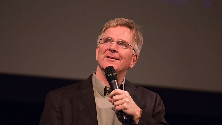 Rick Steves holds a microphone
