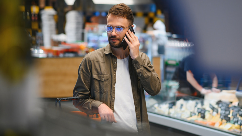 Man talking on phone in deli section of a supermarket