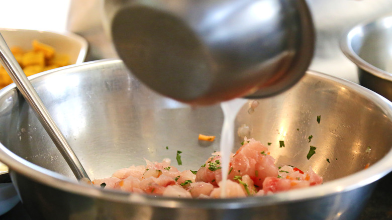 Lime juice being poured into a bowl of raw seafood