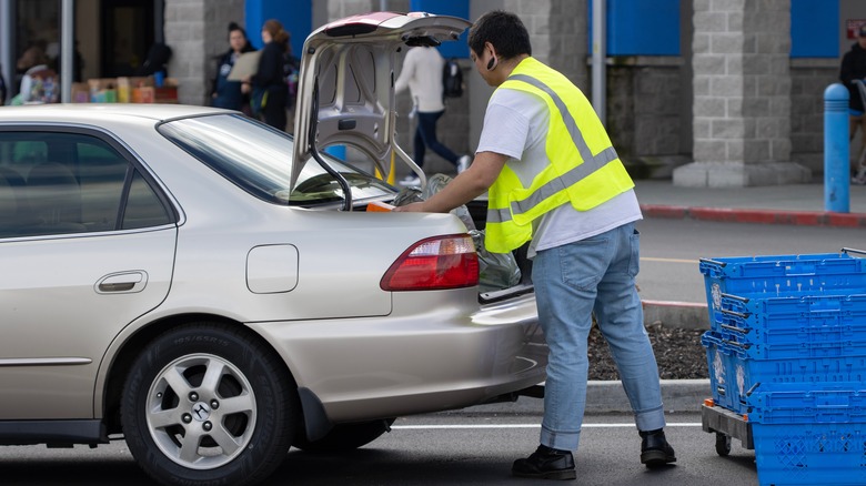 walmart staff loading trunk of vehicle with groceries
