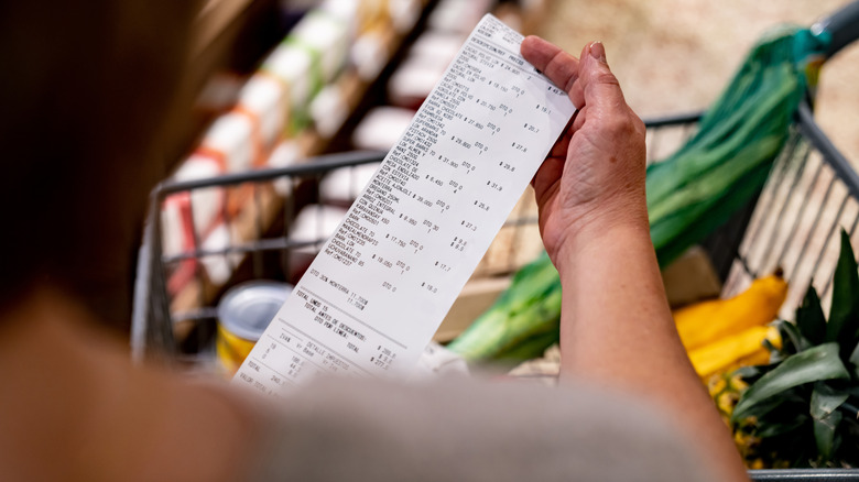woman looking at receipt in grocery store