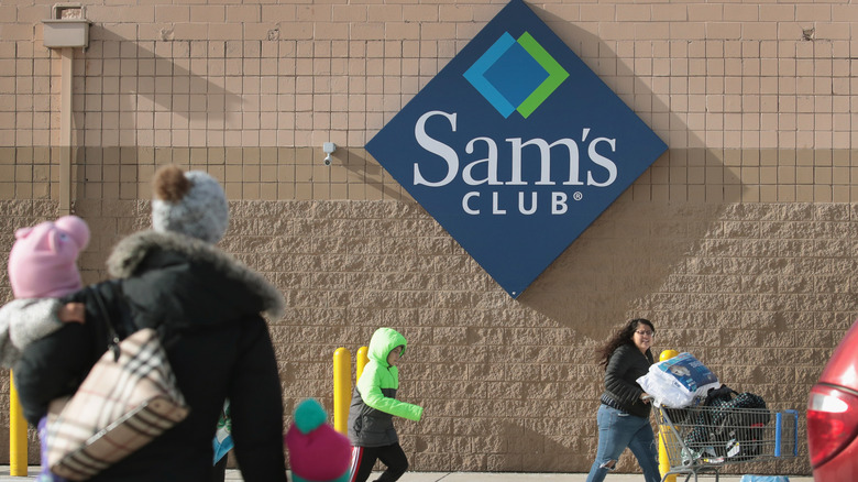 sam's club sign on store with shoppers walking past
