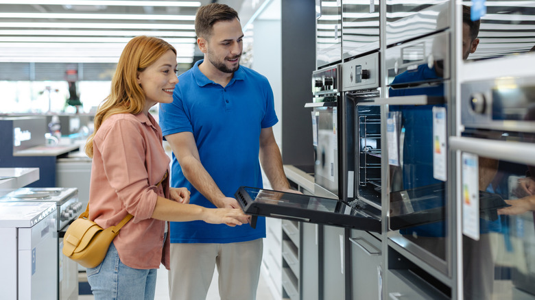 Couple opening up oven in kitchen appliance store
