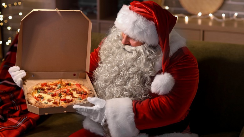 Santa Claus with pizza in box at home on Christmas eve