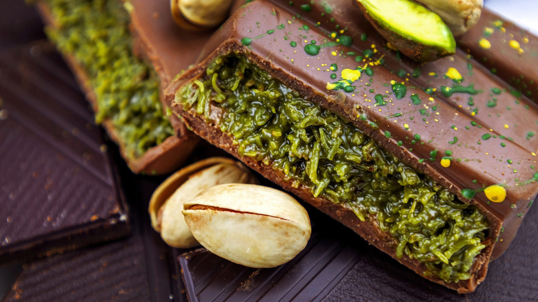 A piece of Dubai Chocolate split into pieces with pistachios next to it