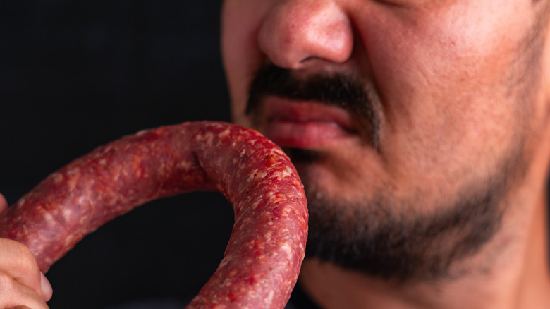 Person sniffing sausage with displeasure