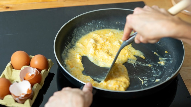 Person cooking scrambled eggs in nonstick pan