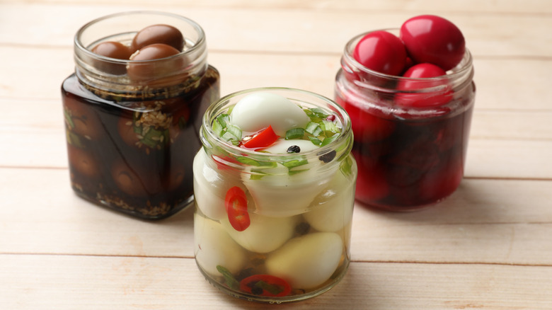 Three jars of eggs in marinades of different colors