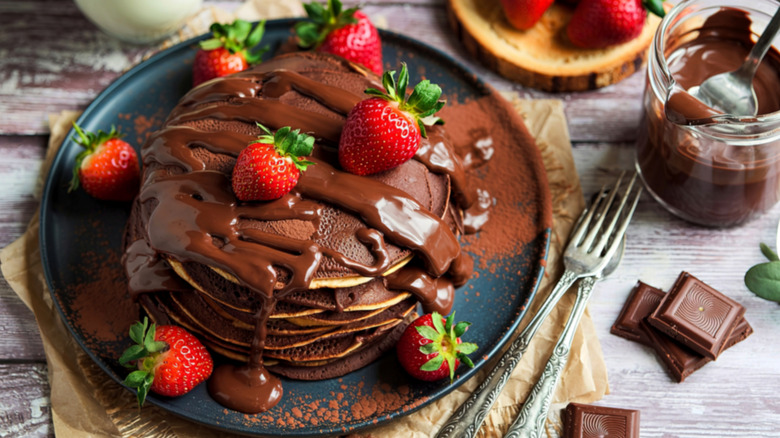 Dark chocolate pancakes covered in fresh strawberries and chocolate syrup