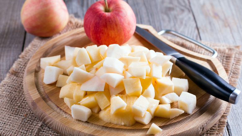 Whole and diced apples on a wooden board