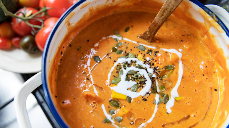 Creamy tomato soup topped with cream and seeds in a bowl