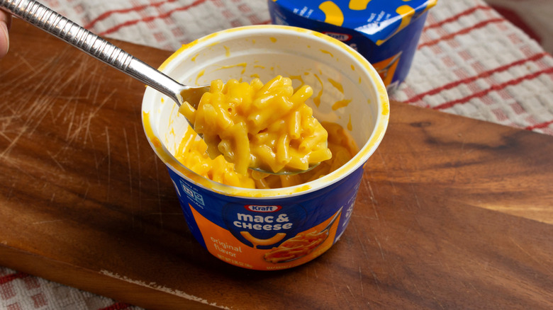 A prepared Kraft mac and cheese microwave cup with a spoon in it