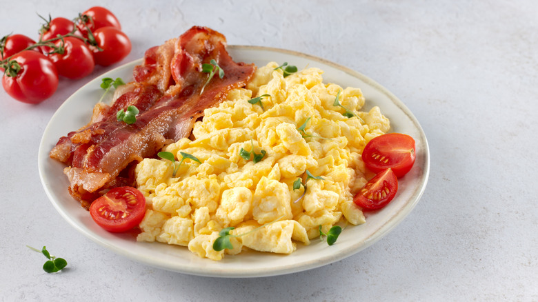 Scrambled eggs with tomatoes and bacon on plate