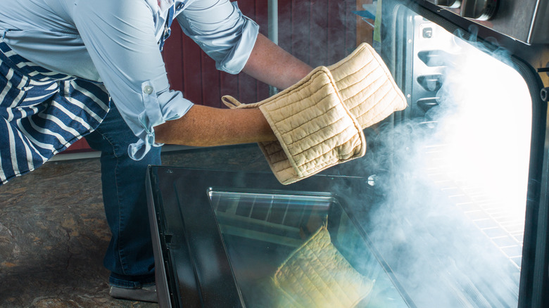 A woman approaches a smoking oven