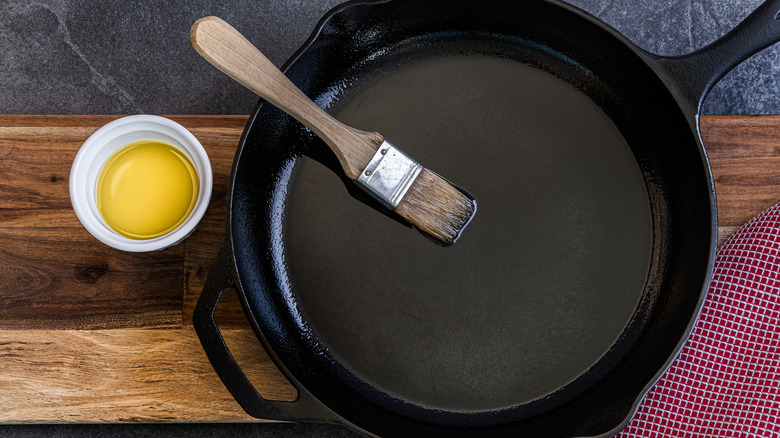 Cast iron skillet coated in oil with brush