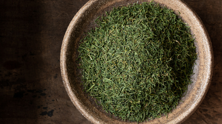 Dill weed piled in a wooden bowl.