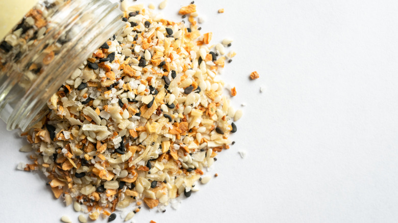Everything bagel seasoning spilling from a spice jar.