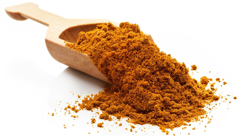 Ras el hanout packed inside a wooden serving scoop.