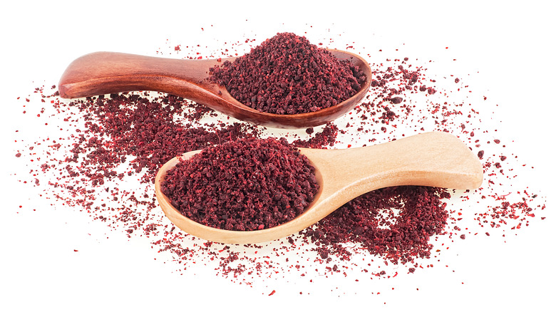 Two wooden spoons filled with sumac