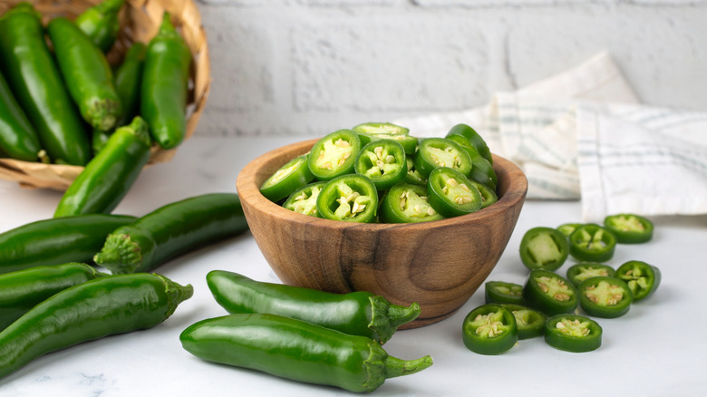Sliced jalapeños in a bowl and whole jalapeños