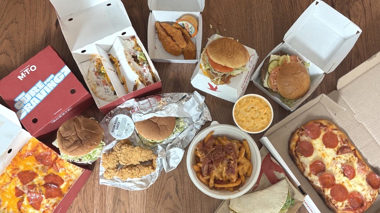 Hot food in boxes and wrappers from Sheetz and Wawa on table, including loaded fries, tacos, and chicken strips