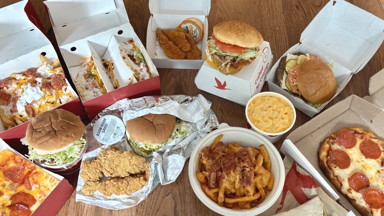 Hot food from Sheetz and Wawa in boxes and wrappers on table, including chicken strips, mac and cheese, and burgers