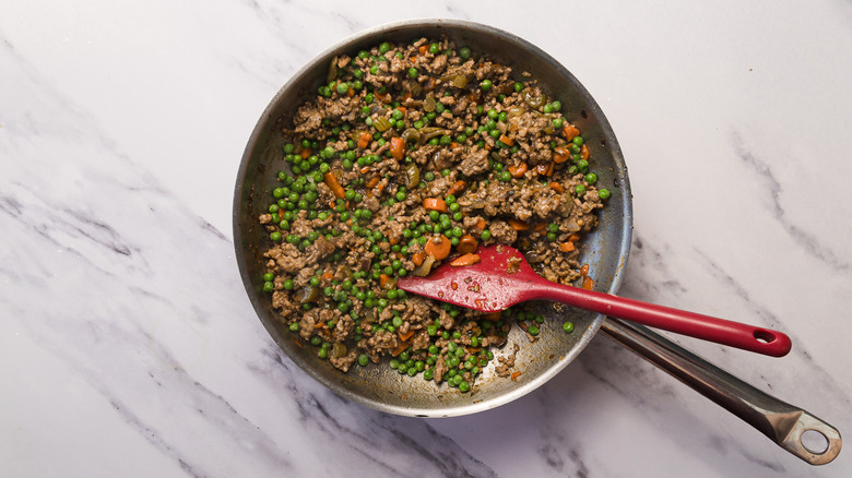 Cooked lamb filling with peas in pan