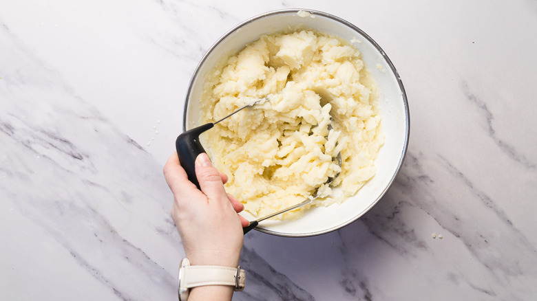 Mashing potatoes in bowl