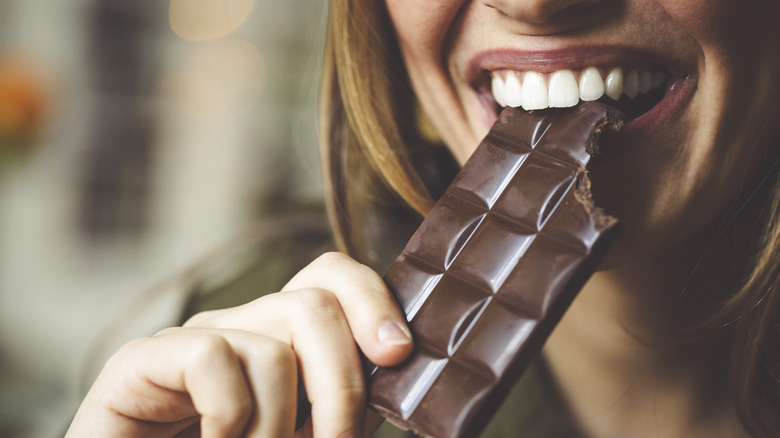 Close-up of woman biting into a chocolate bar
