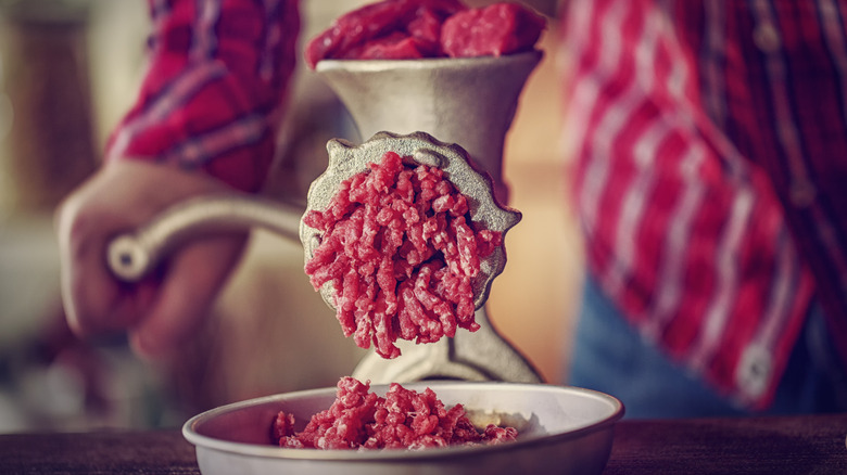 Fresh minced beef coming out of a manual meat grinder