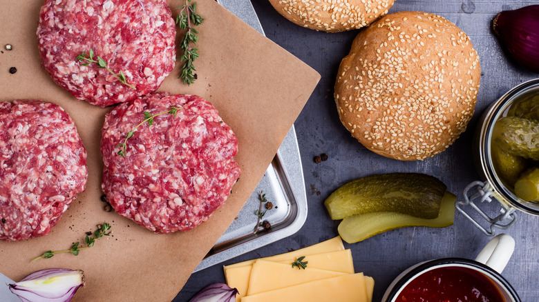Raw beef burger patties, buns, and pickles