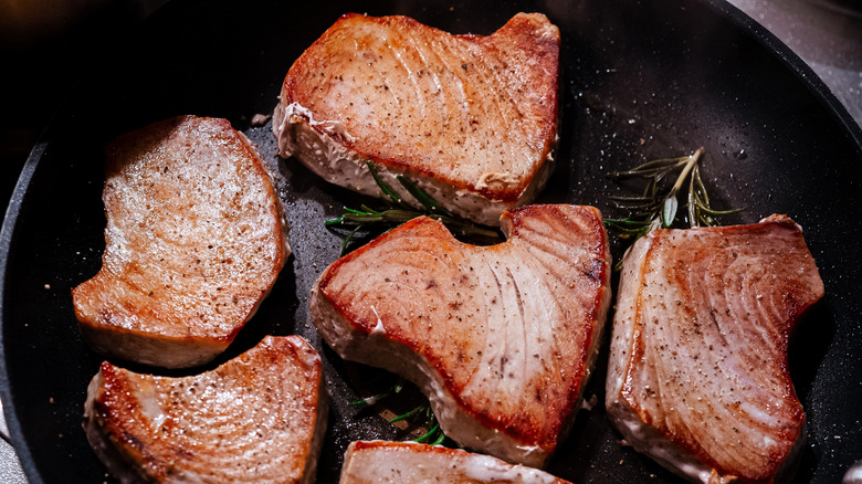 Seared tuna steaks in pan with rosemary sprigs