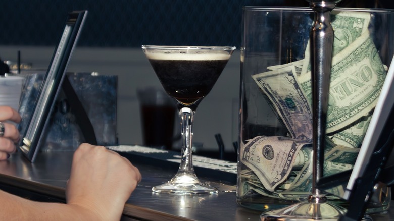 Espresso martini on bar with cash tip jar