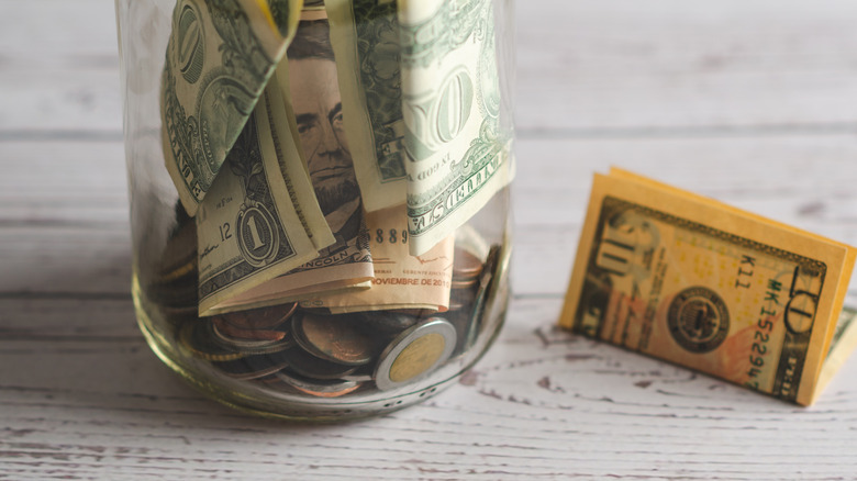 A tip jar on a counter with a $10 bill