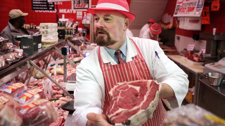 Butcher showing cut of meat to customer