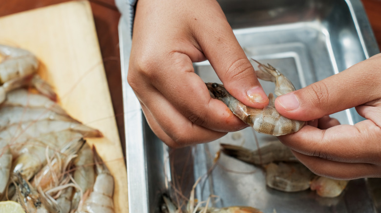 A person peeling a shrimp.