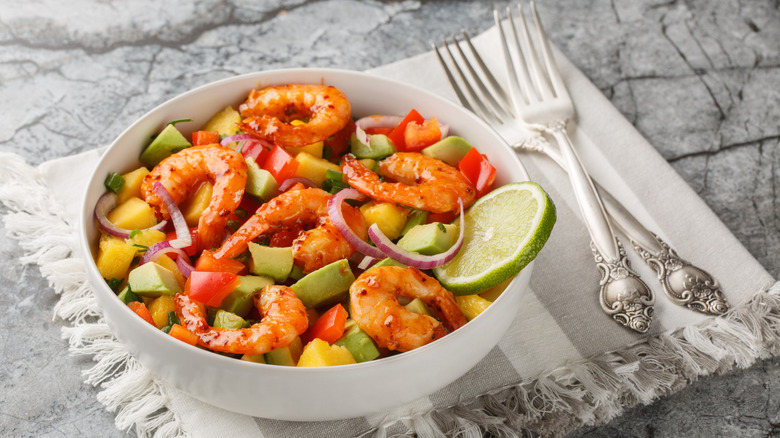 Prawn salad with avocado, lime, red bell pepper, and other veggies in a bowl