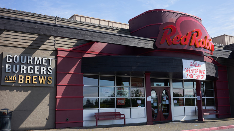 Deserted Red Robin restaurant with delivery and to-go sign above front doors