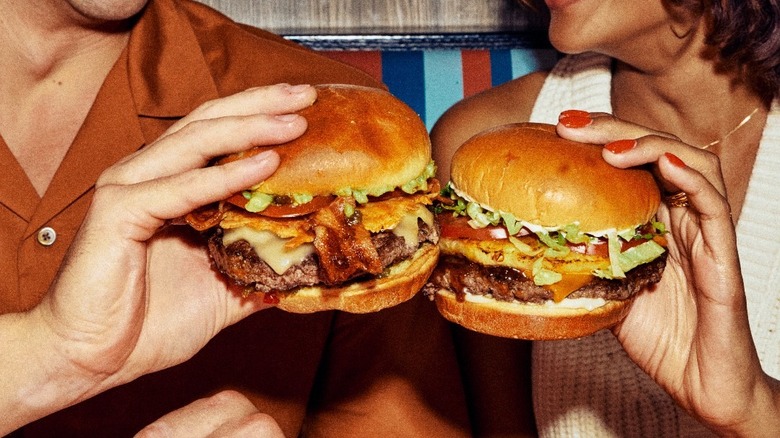 two people holding burgers