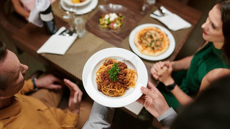 Server bringing Italian dish to restaurant table
