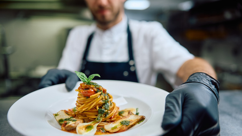 close up of chef with a plate with spaghetti