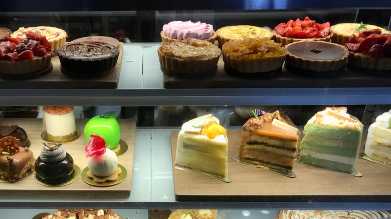A variety of cakes and pastries displayed in a deli case