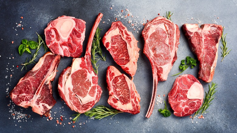 Raw, premium cuts of steak with herbs around