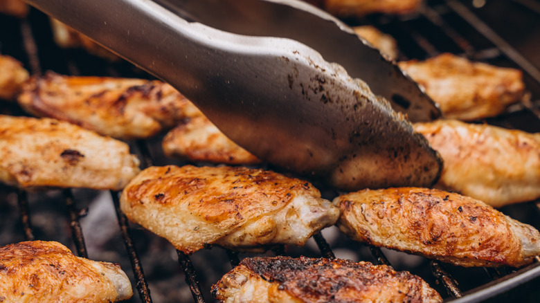 tongs flip chicken legs and thighs on grill