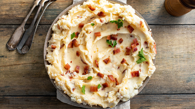 A top-down view of bacon mashed potatoes with parsley in it