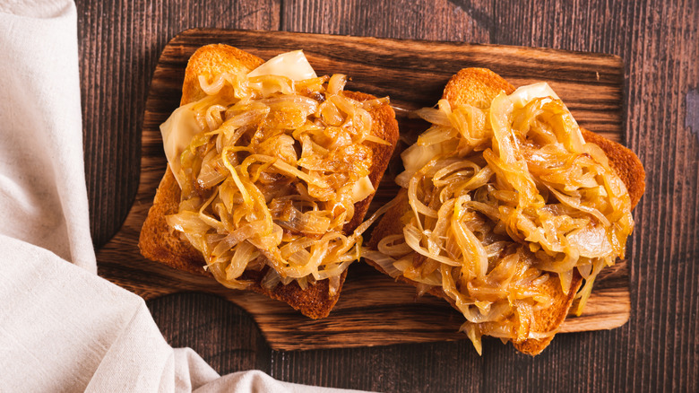 Caramelized onions on toast on a wooden cutting board