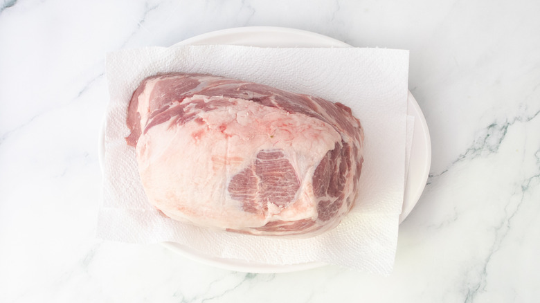 Raw pork butt on a large white platter