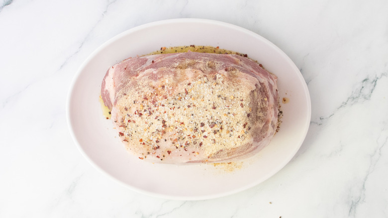 Seasoned raw pork butt on a white platter